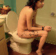 A skinny girl with tattoos and punky red and green hair takes a piss and a shit while sitting on a toilet in 2 scenes. Plopping sounds are more noticeable in the second scene. Presented in 720P HD. About 7 minutes.